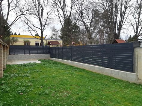 Antracit színű kerítés világos homlokzatú házzal
